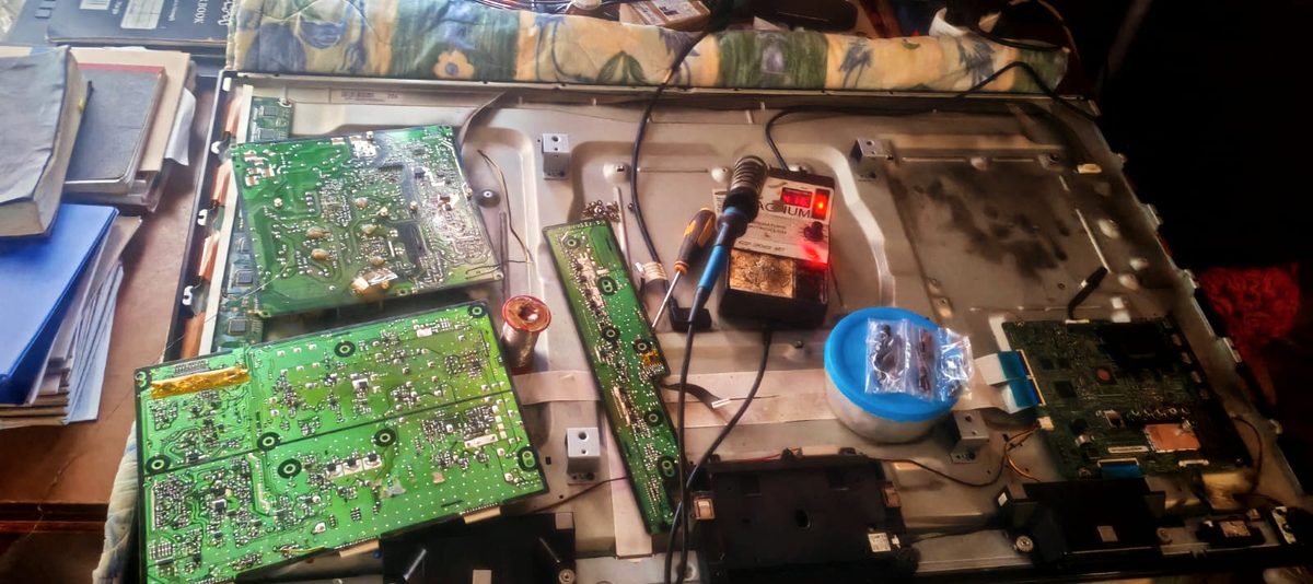 Circuit boards removed from a television during a repair, with a soldering iron on the workbench
