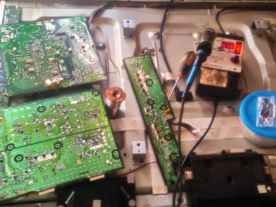 Opened television showing power and main boards during repair